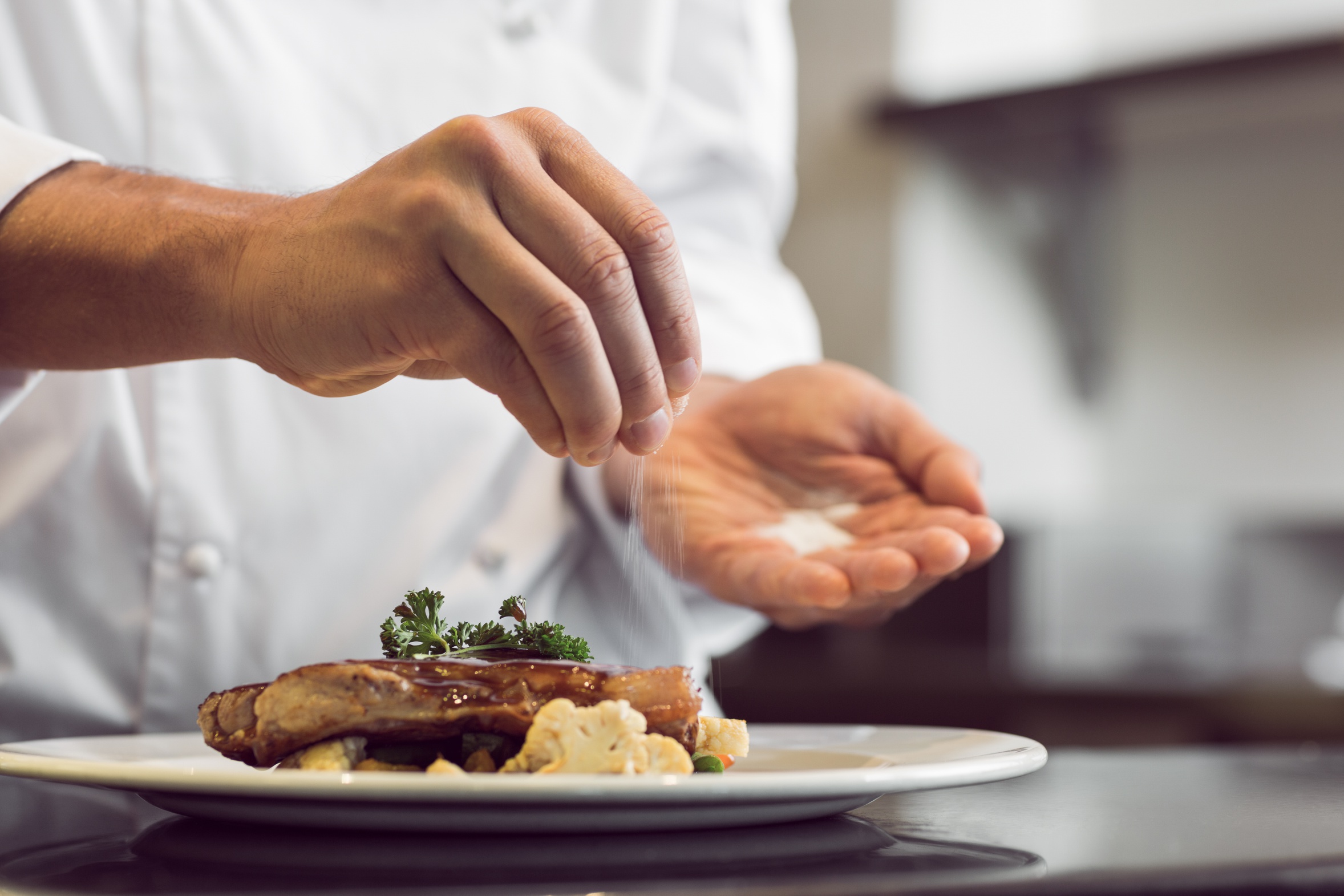 Closeup mid section of a chef putting salt Catering by Dinnerzeit